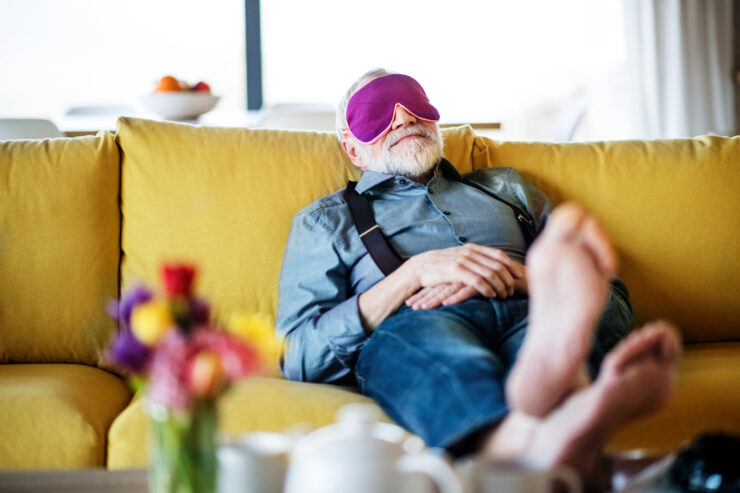 Senior man relaxing on a couch with an eye mask