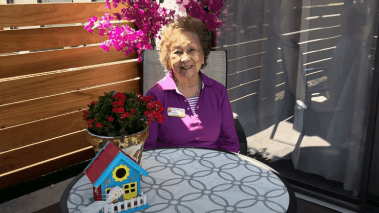 A resident enjoying the outdoors with flowers and a decorative house