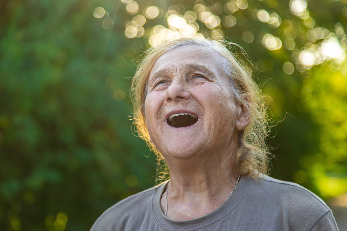 Elderly woman smiling outdoors with sunlight