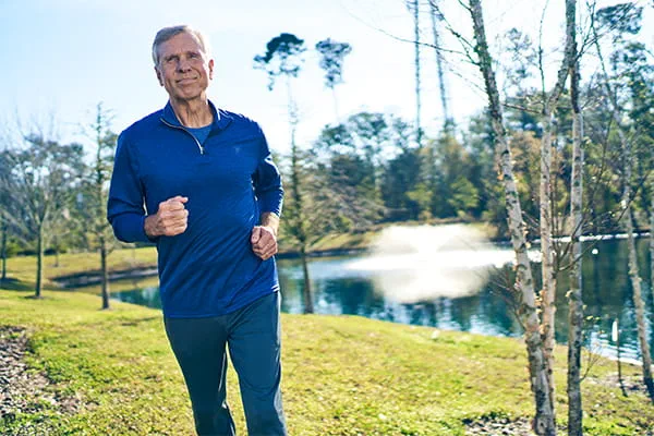 Senior man jogging by a serene lake
