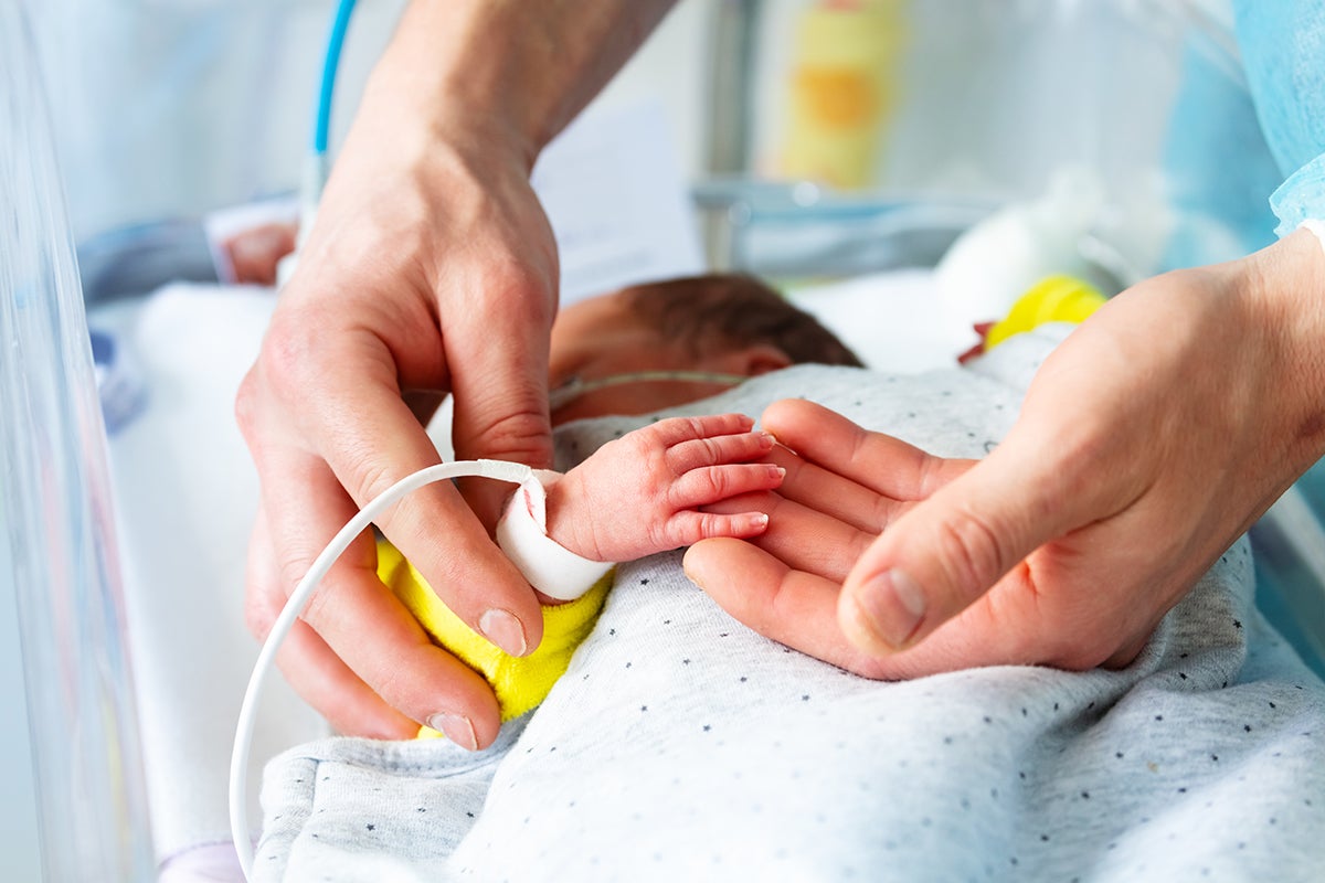 A caregiver holding a newborn's hand