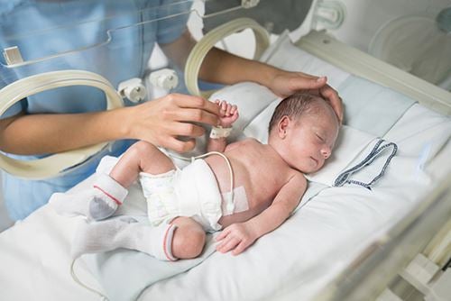 A healthcare professional tending to a newborn in an incubator