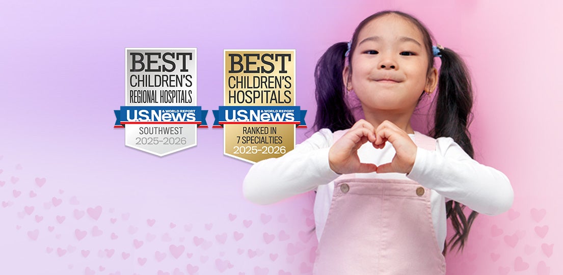 Child smiling and making a heart gesture