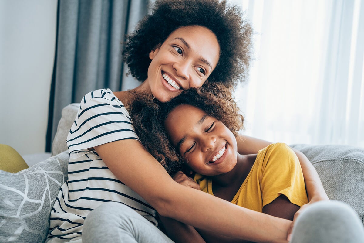 Smiling mother and daughter embracing in a cozy indoor setting