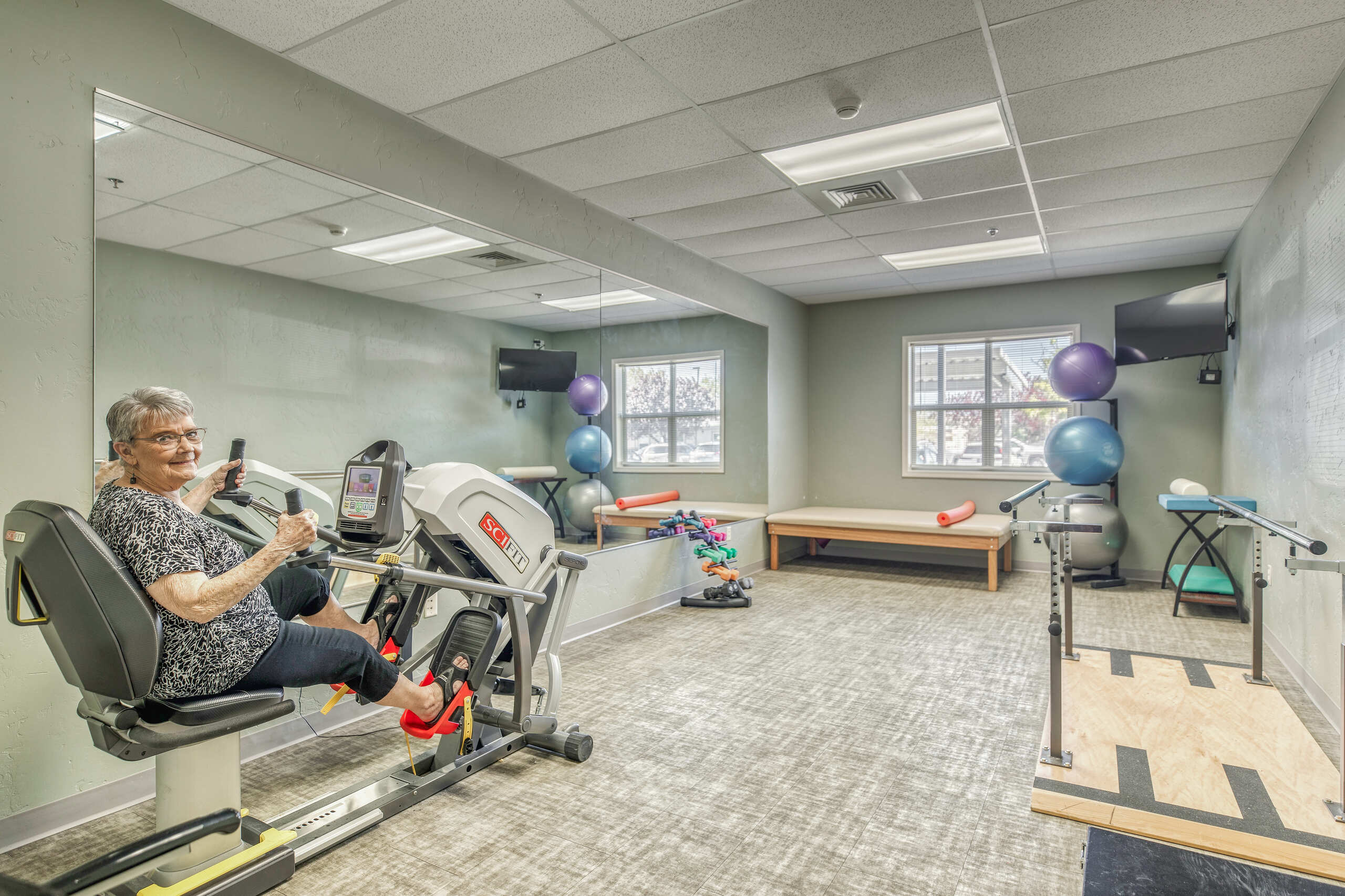 Resident exercising in a fitness room with gym equipment