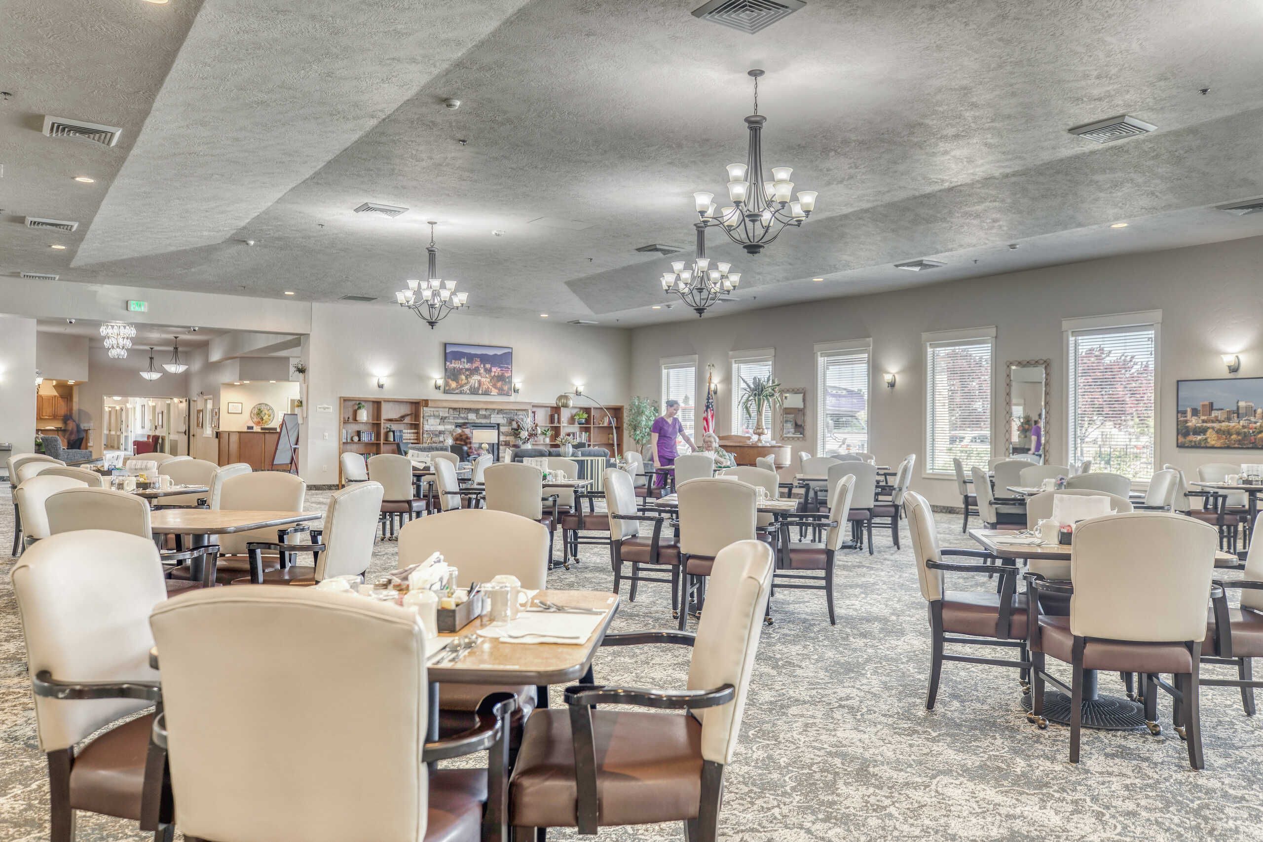 Dining area with tables and residents in a well-lit room