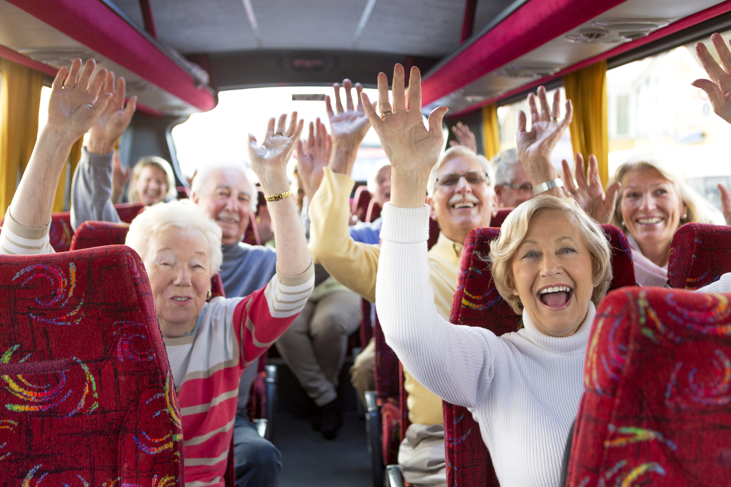 Residents enjoying a bus trip with raised hands