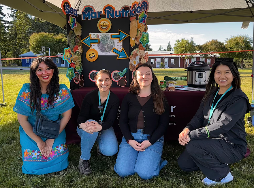Group of four women smiling at a community event.