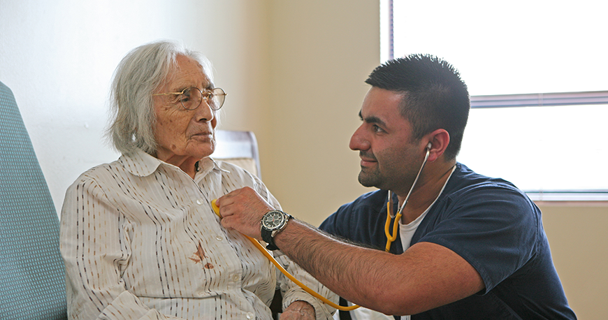 Nurse checking an elderly woman's heartbeat