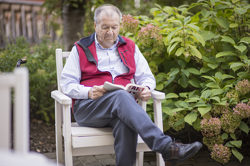 Elderly man reading a book in garden