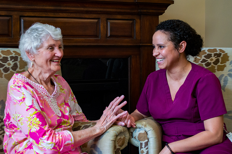 A caregiver and resident happily interacting indoors.