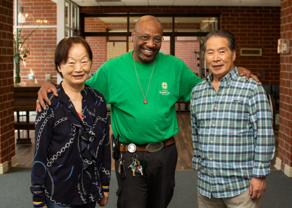 Three smiling residents posing together indoors.