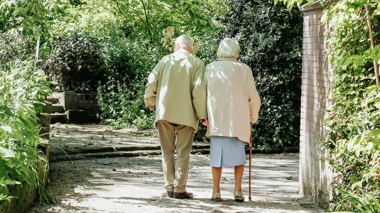 Elderly couple walking hand in hand in a garden