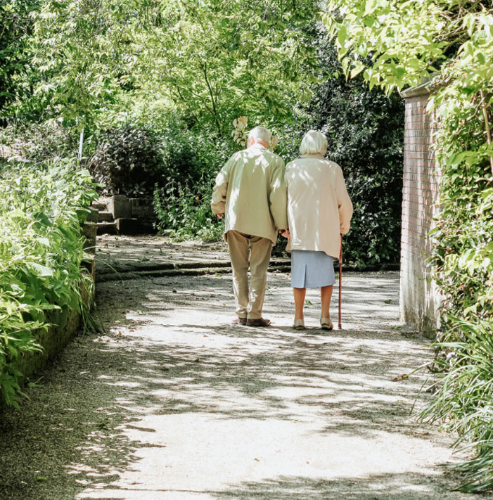 Elderly couple walking hand-in-hand on a path