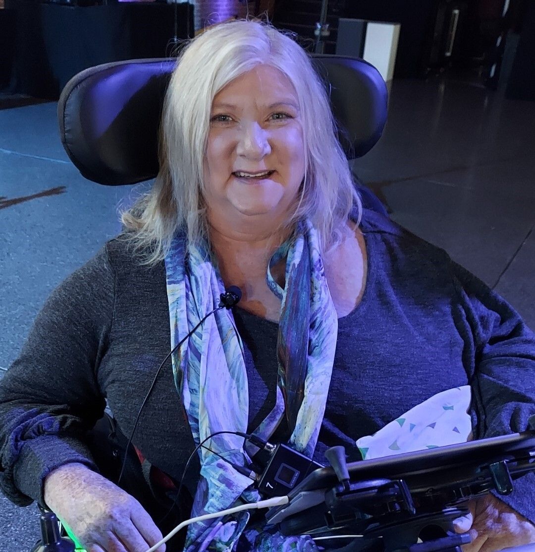 Woman smiling in a wheelchair at an event.