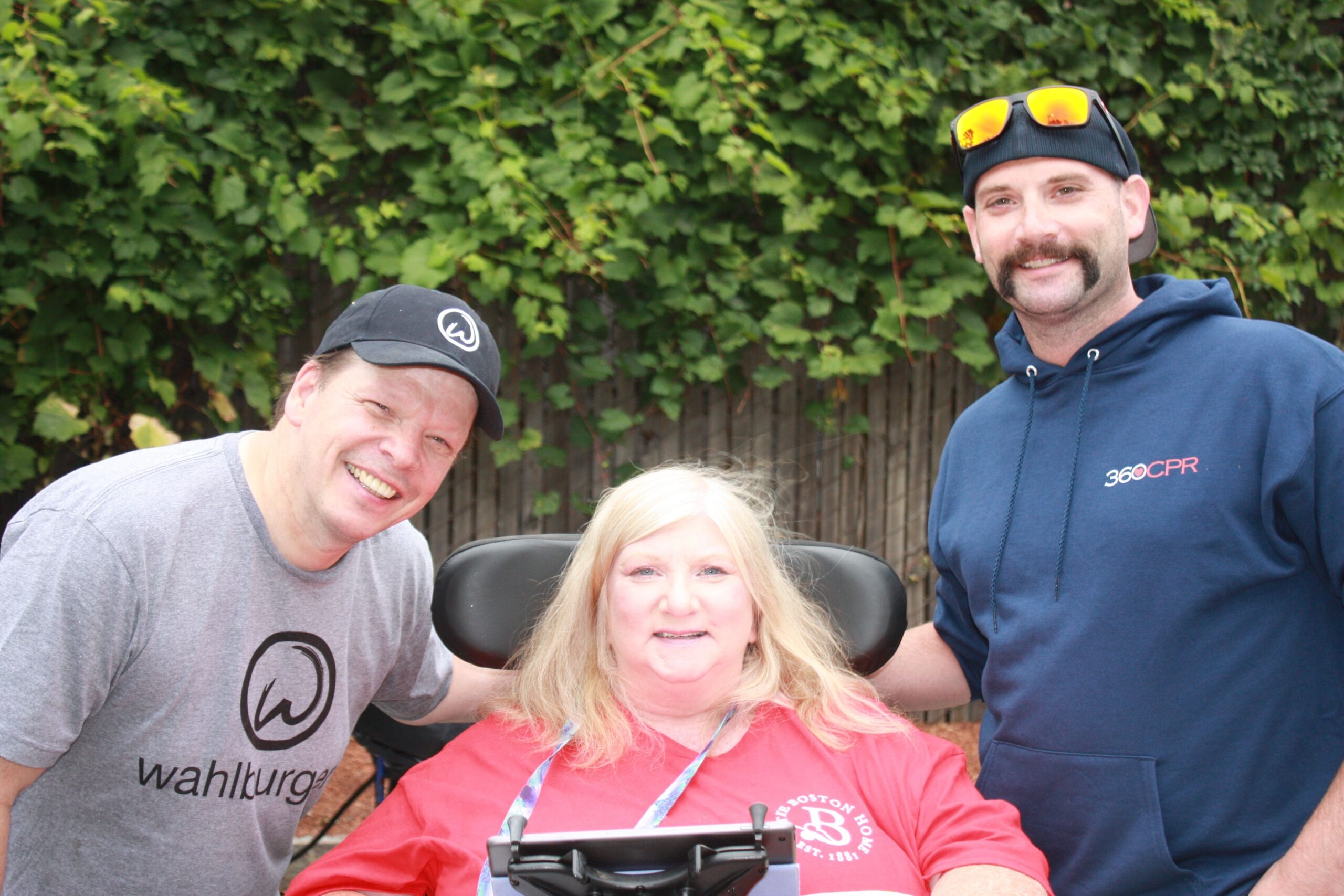 Three people smiling in an outdoor setting.