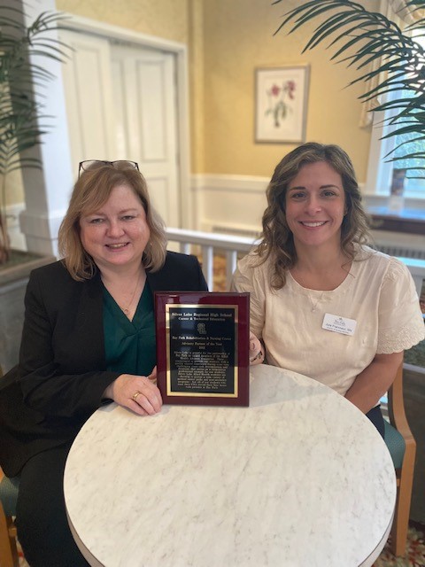 Two women holding an award in a common area