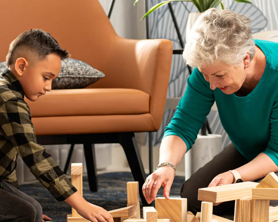 Grandmother playing with grandson using building blocks.