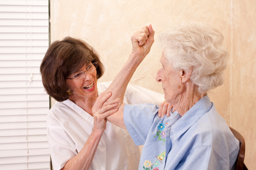 Caregiver assisting an elderly woman during therapy