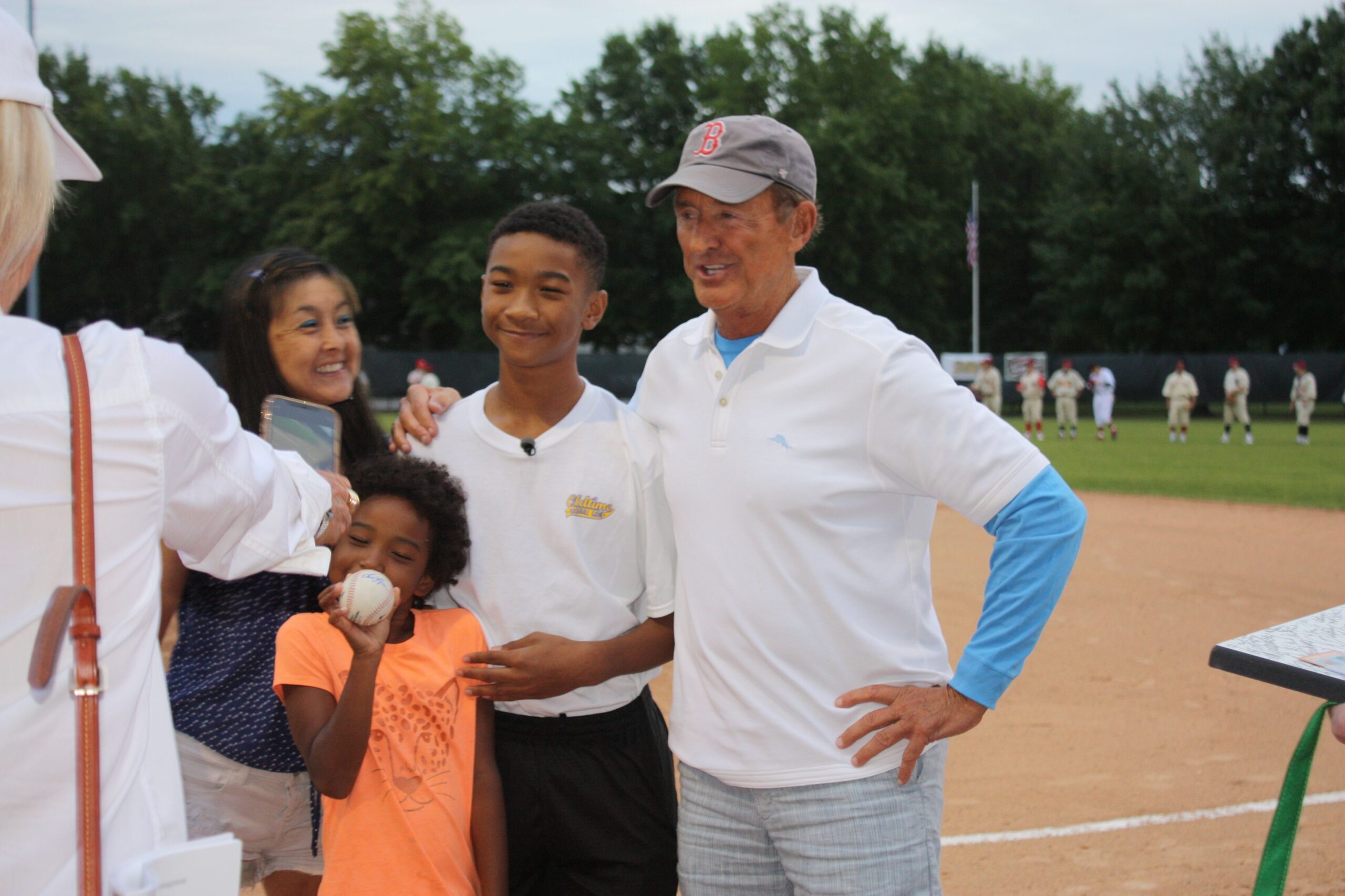 Family posing together at a baseball field event.