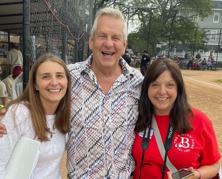 Three smiling individuals at an outdoor event.