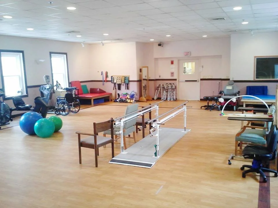 Rehabilitation room with therapy equipment and seating.