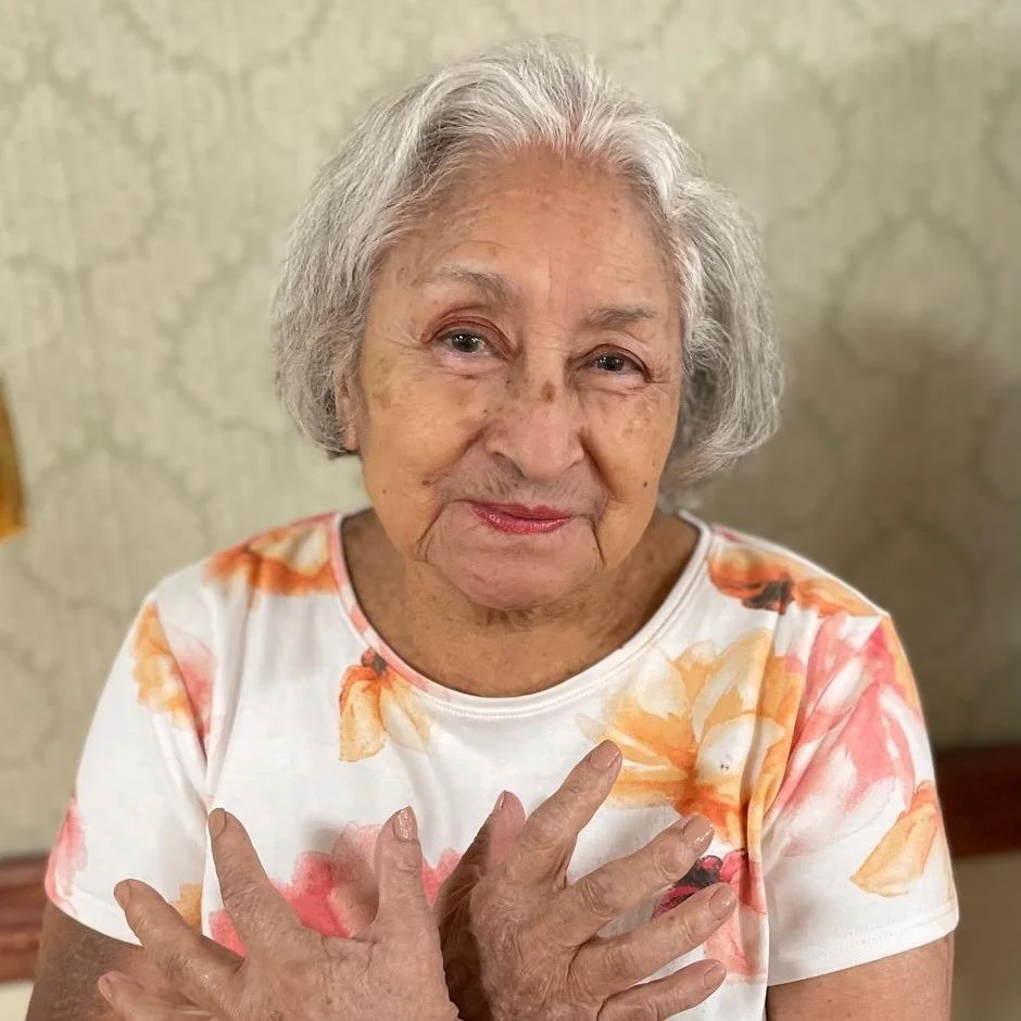 Elderly woman smiling warmly with floral shirt