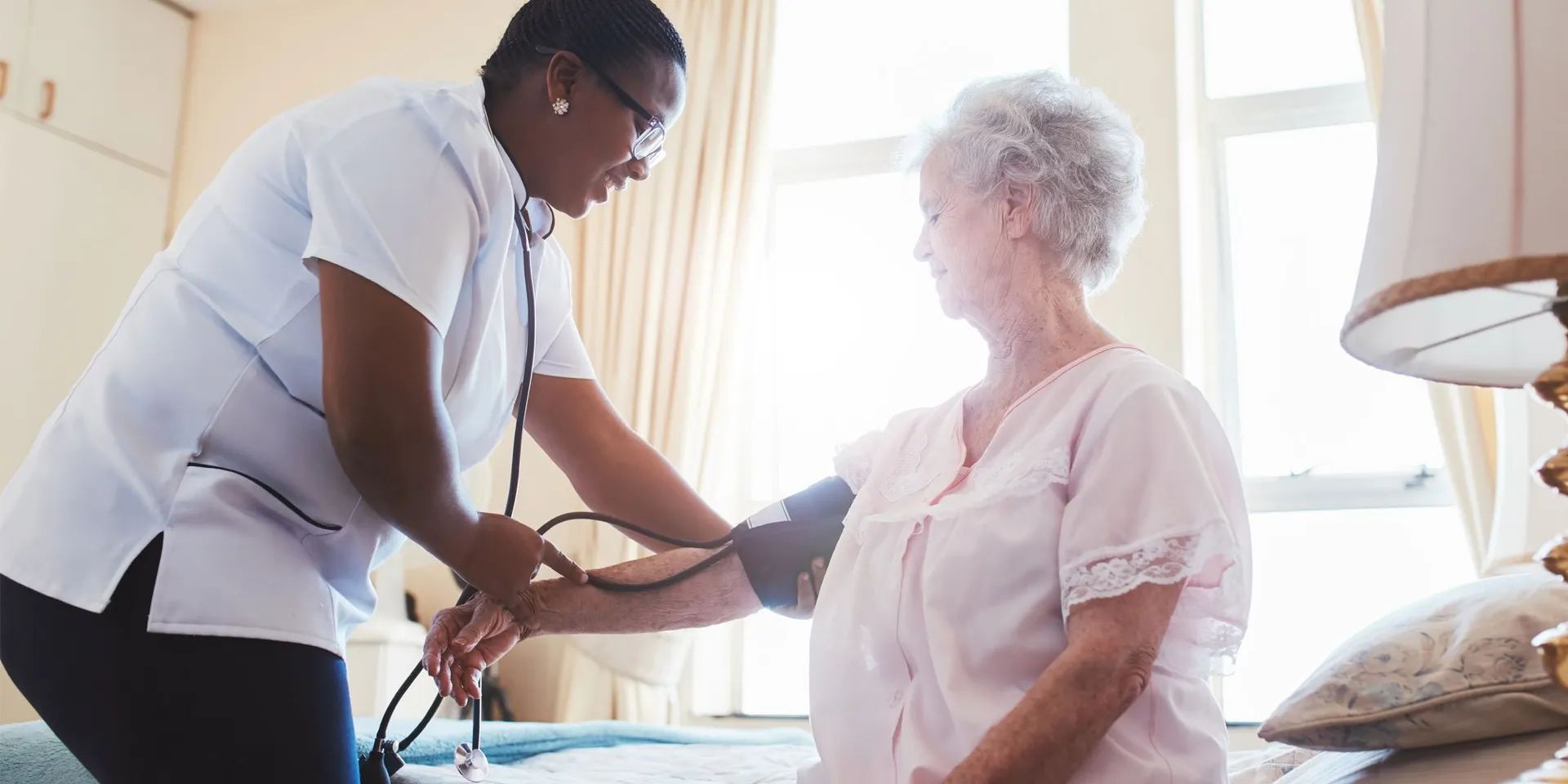 Healthcare worker measuring blood pressure of a senior resident