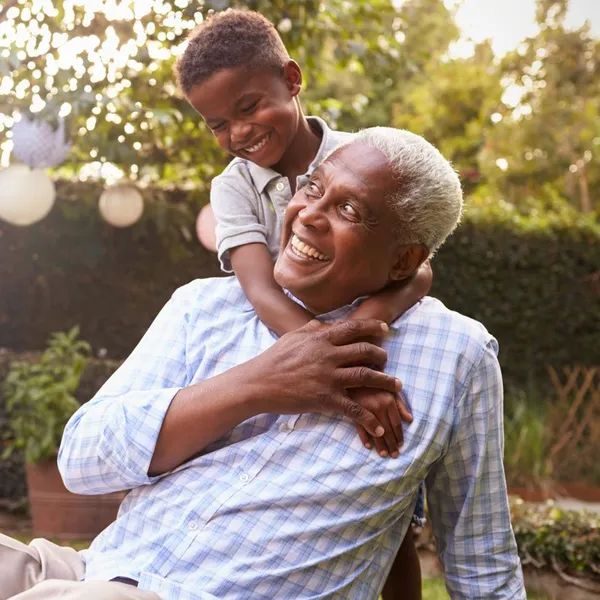 Elderly man playing with a young boy in a garden.