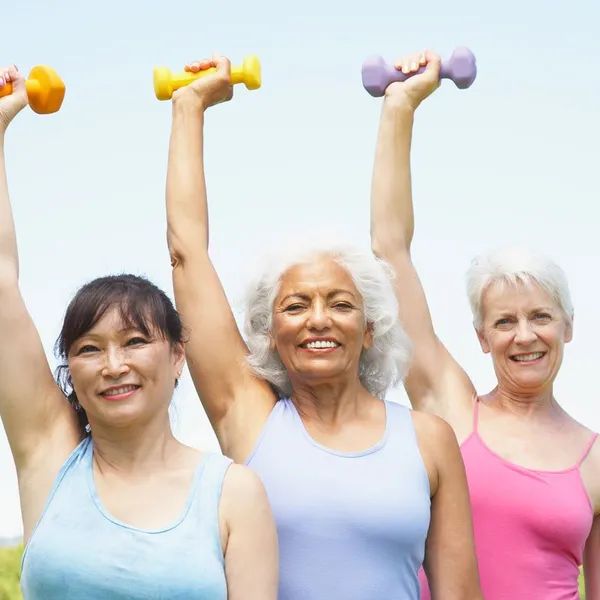 Three women exercising with dumbbells outdoors