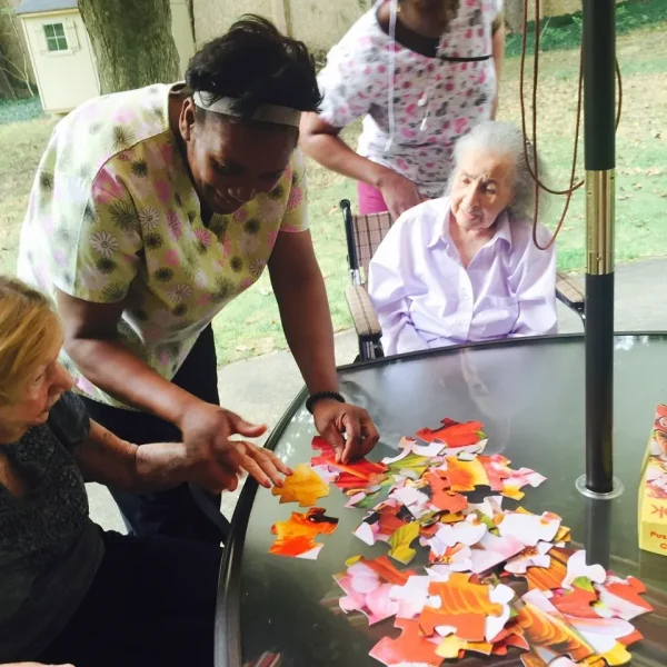 Residents and staff engaging in a puzzle activity outdoors.