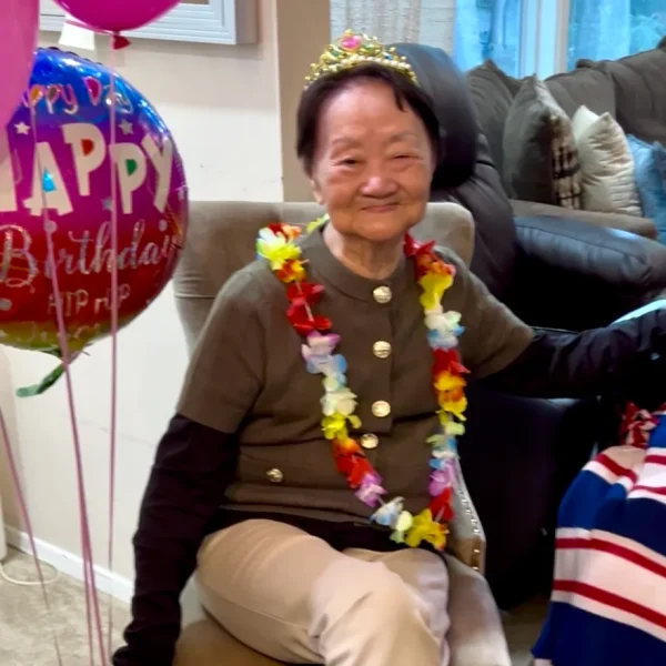 Resident celebrating a birthday with balloons and a lei.