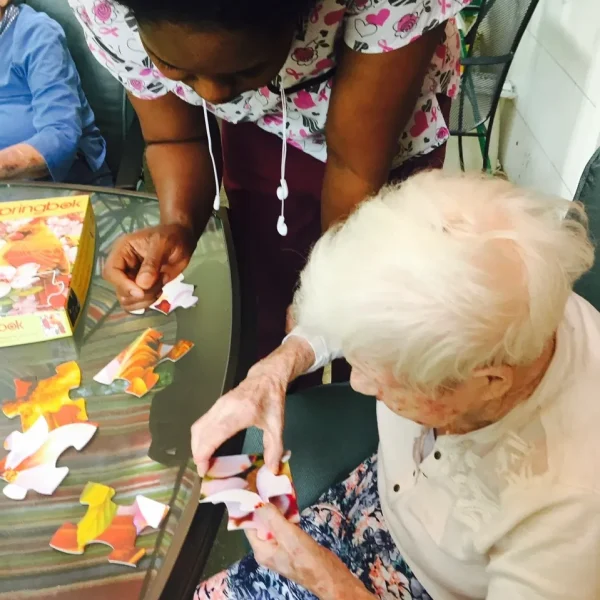 Staff assisting a resident with a puzzle activity.