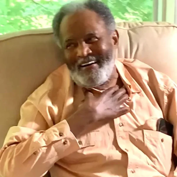 Smiling elderly man sitting comfortably indoors.