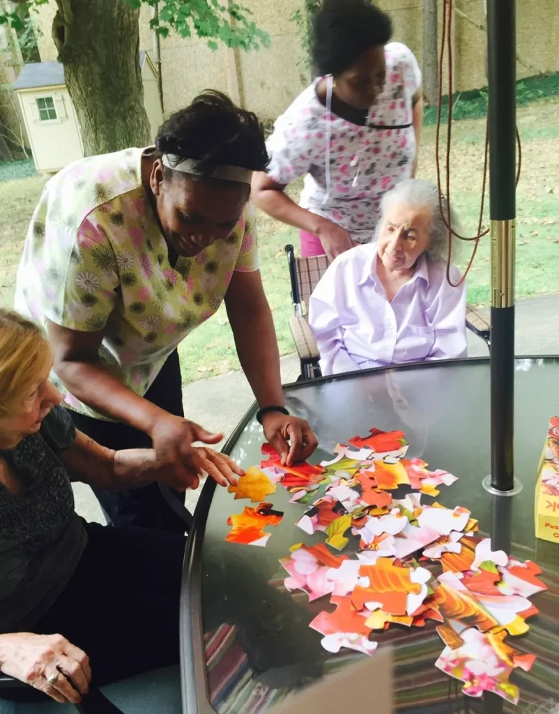 Residents and staff engaged in a puzzle activity outdoors.