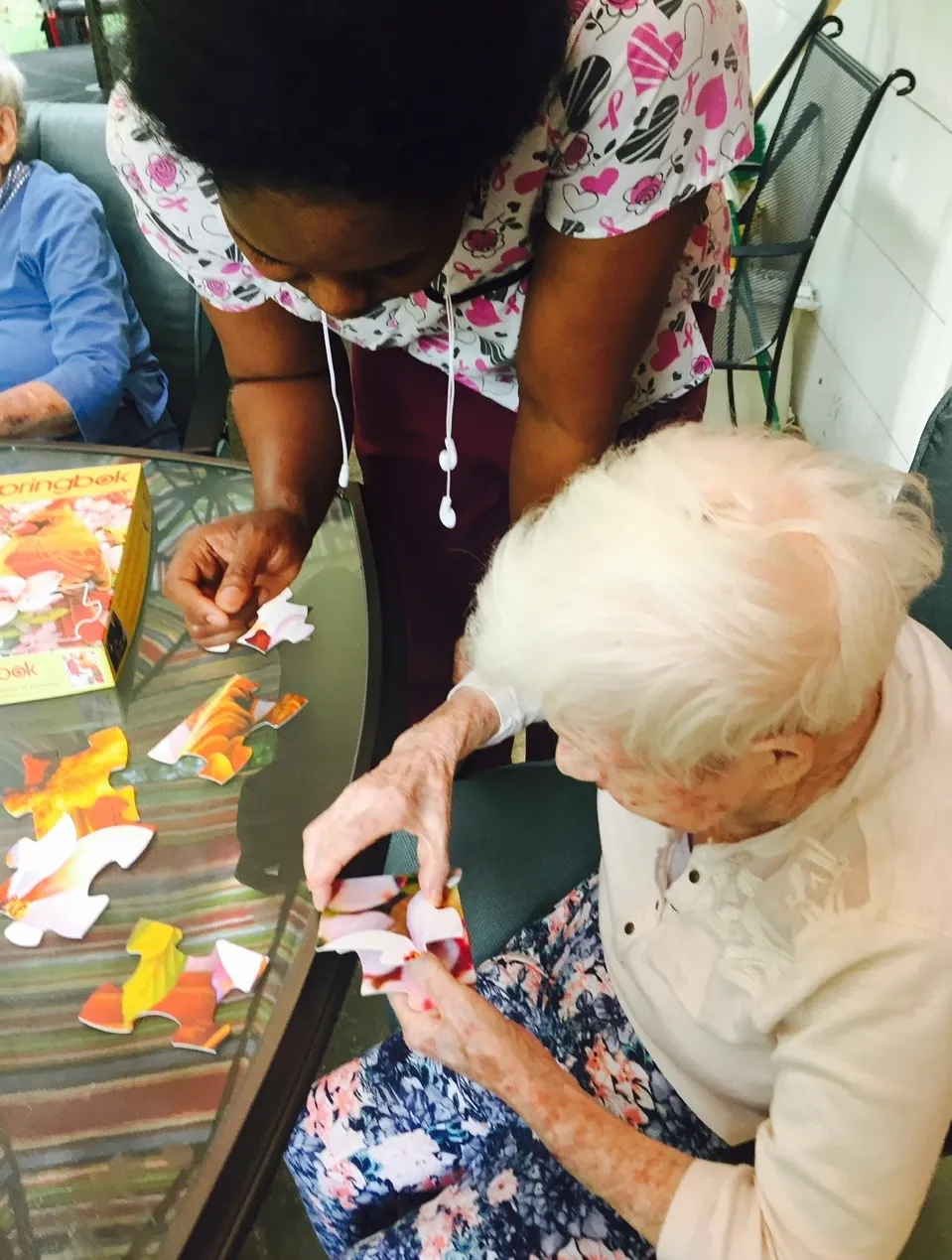 Senior resident and caregiver working on a puzzle together.