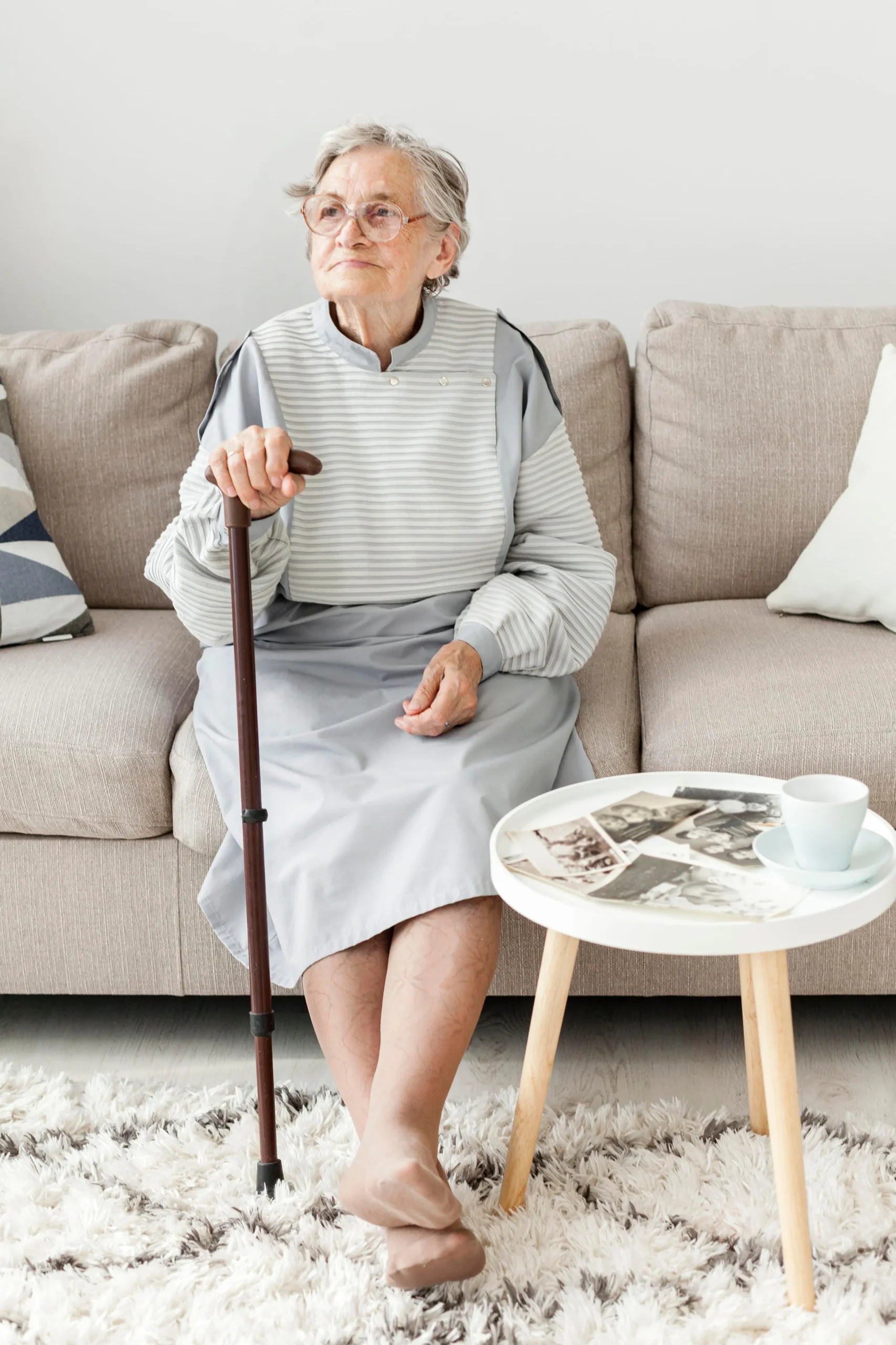 Elderly woman sitting on a couch with a cane