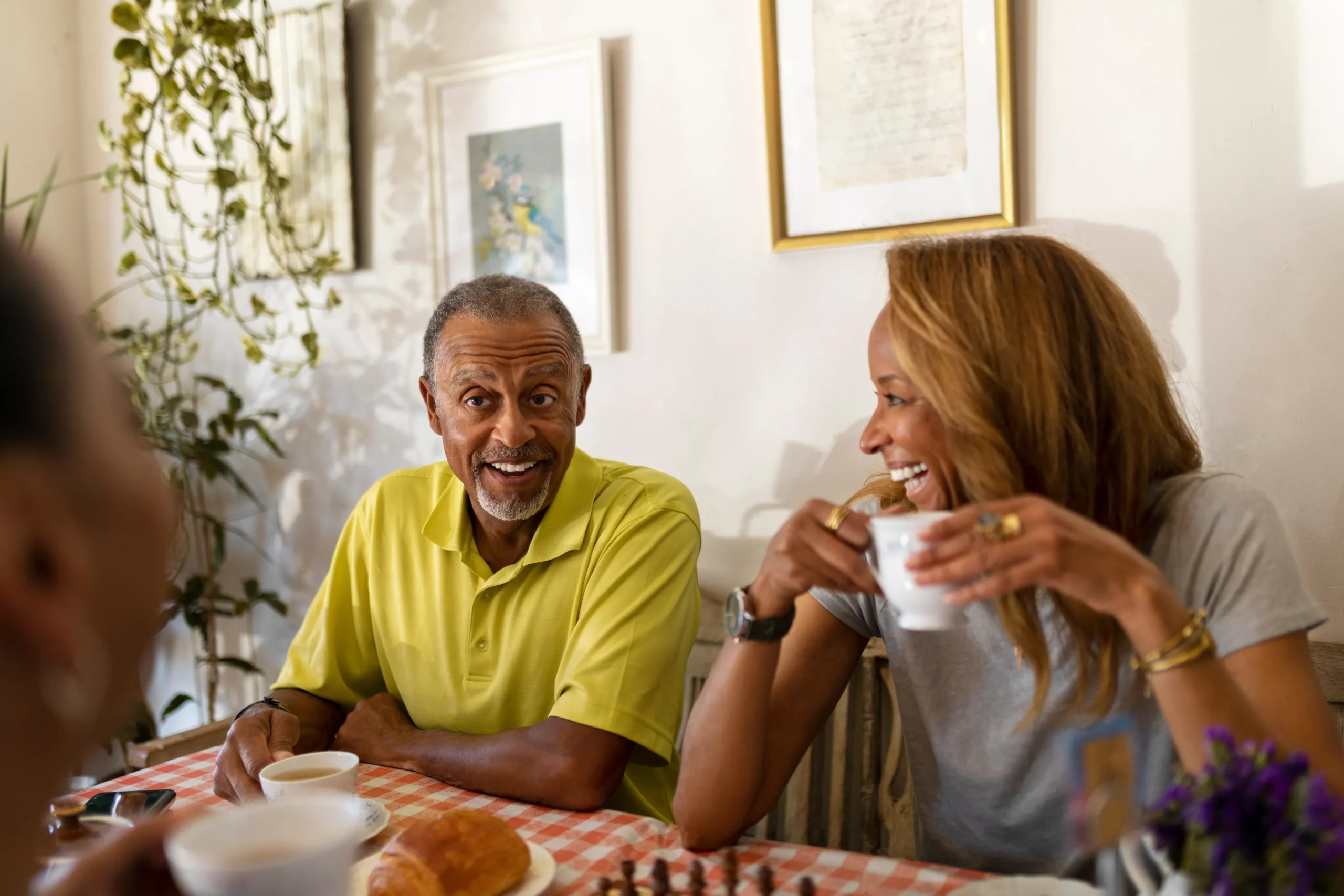 Residents enjoying tea and conversation at a dining table.