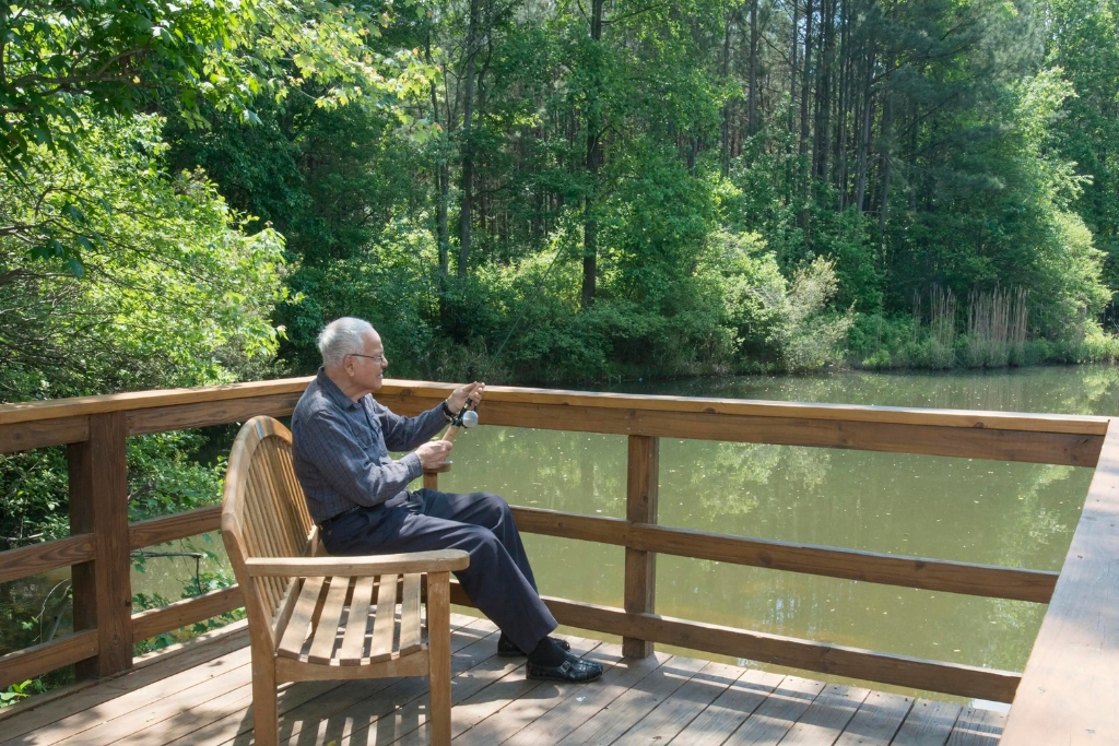 Elderly man fishing from a wooden deck