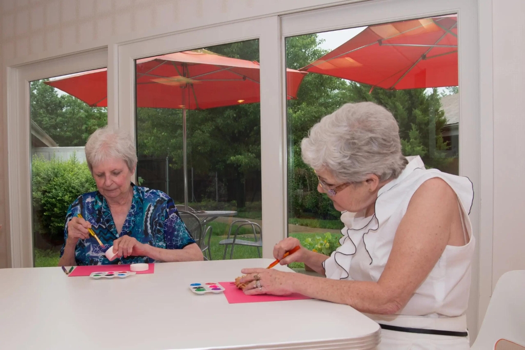 Two residents engaging in an art activity indoors.