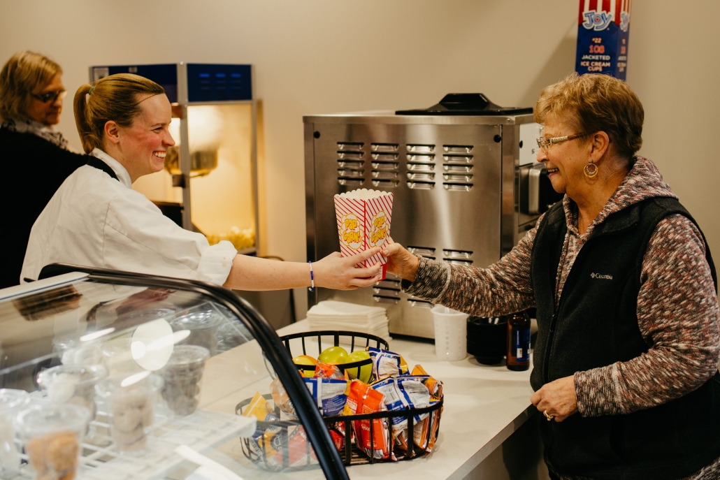 Staff serving popcorn to a resident in a dining area.