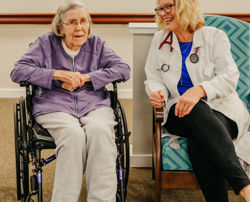 A resident smiling with a caregiver in a cozy setting.
