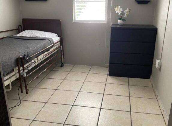 Simple resident room with a bed and dresser.