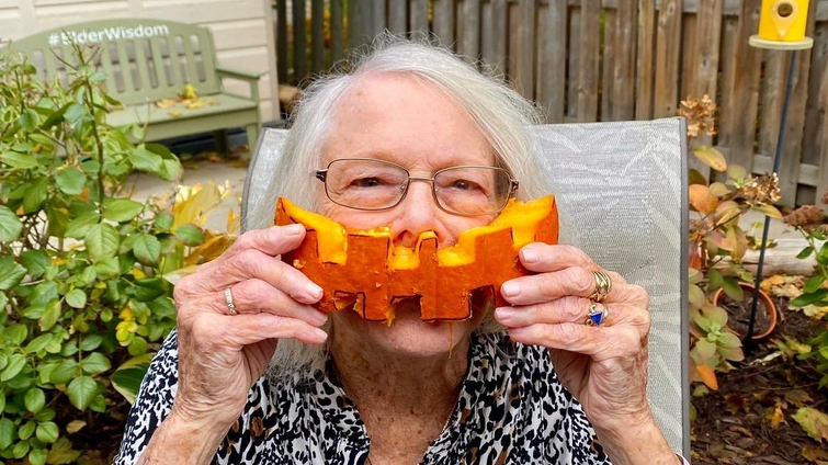 Senior woman enjoying an outdoor activity with a pumpkin.