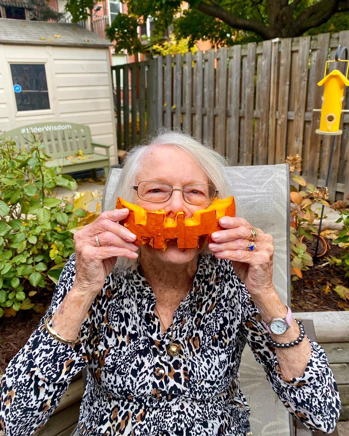 Senior woman playfully holding a pumpkin