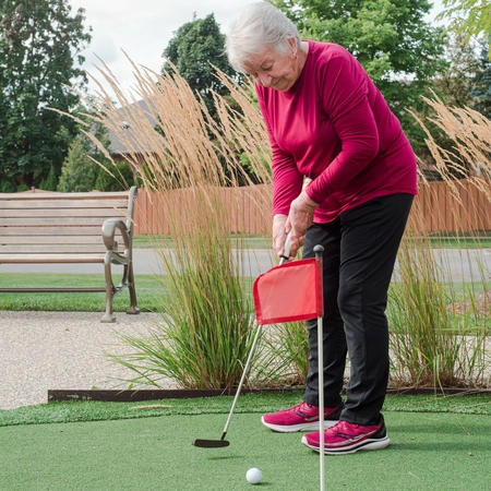 Senior woman practicing putting on a mini-golf green.