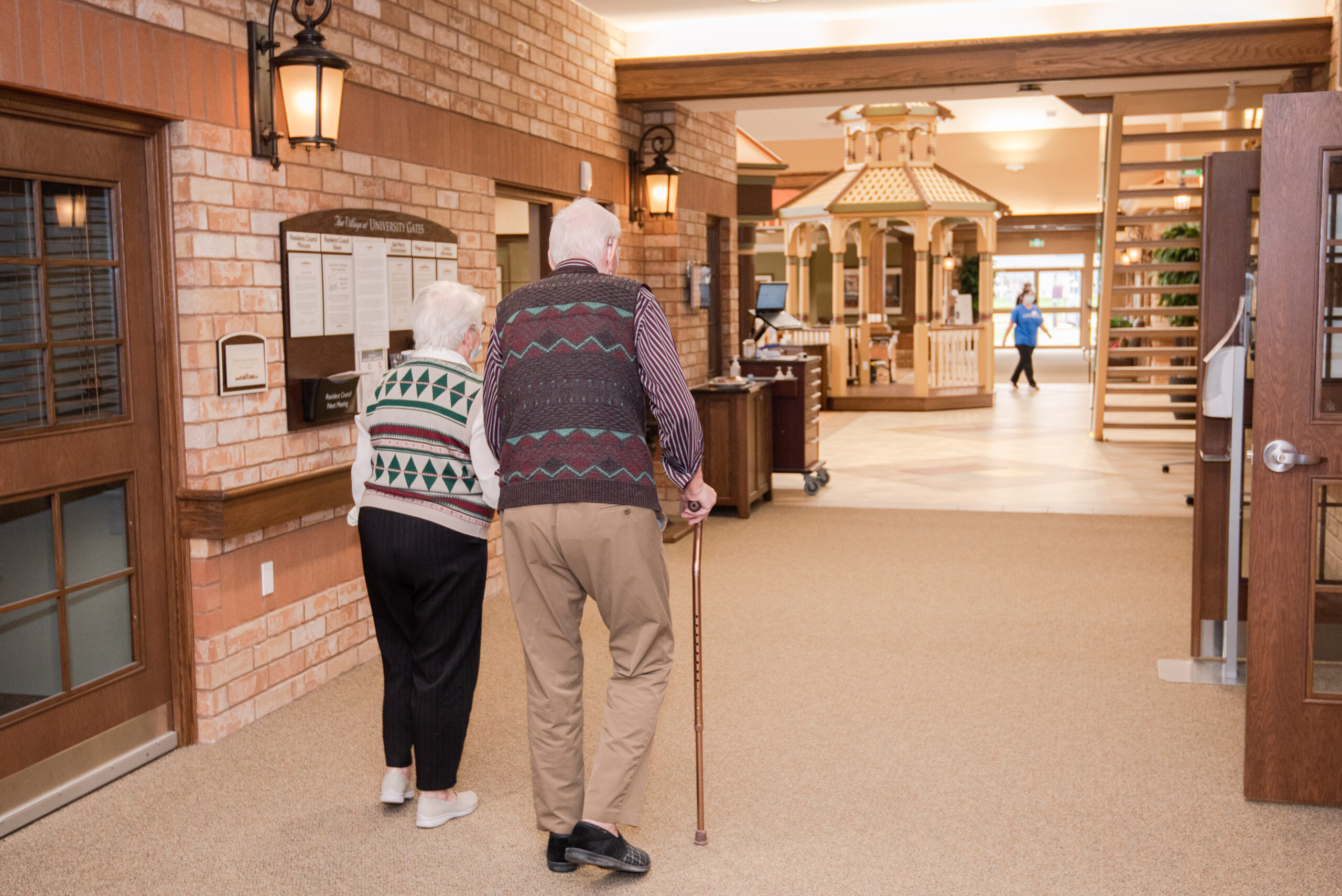 Two elderly residents walking together in a hallway.