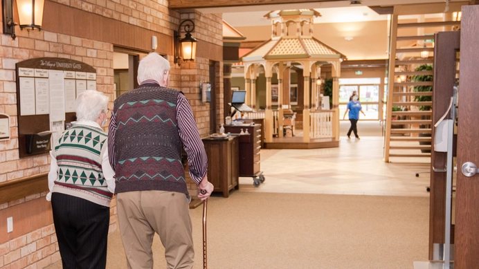 Residents walking in a facility interior with decor.