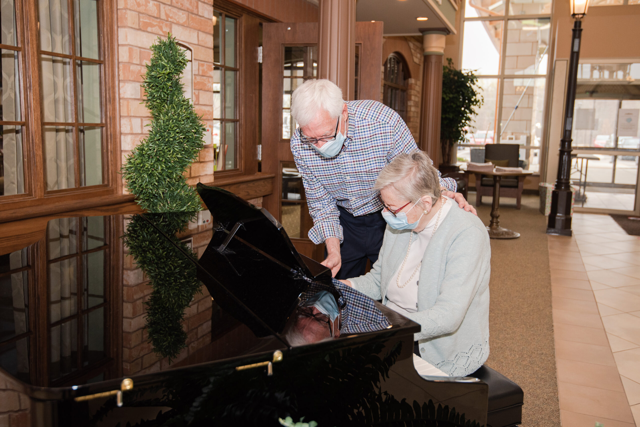 Residents enjoying music at a piano in the common area.