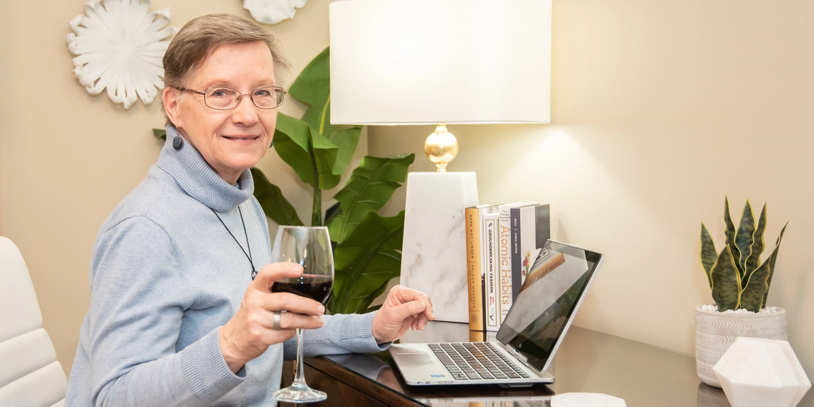 Senior resident enjoying a drink at a desk.